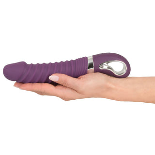 Wärmender Soft Vibrator in Lila in einer Hand gehalten